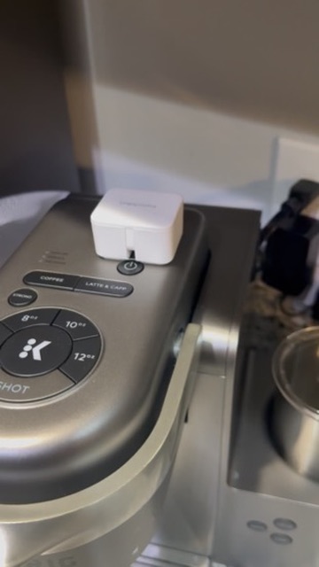 A SwitchBot button-presser on top of a coffee pot